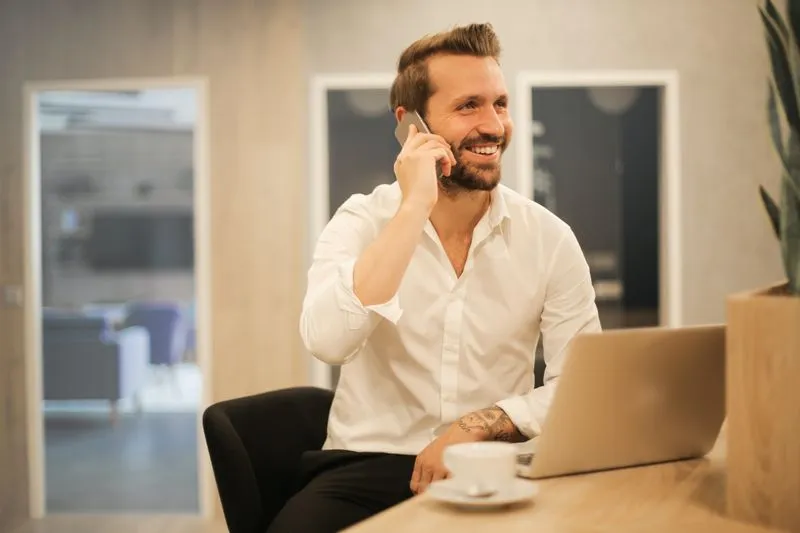 Smiling recruiter on a phone call at a desk with a laptop